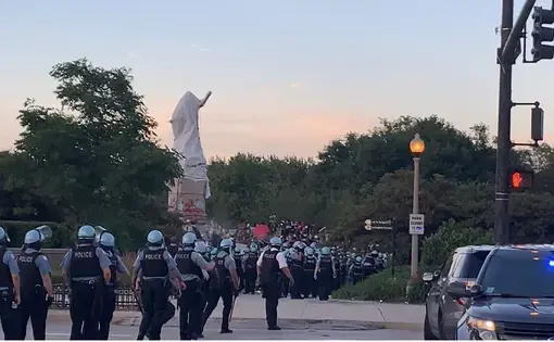 Dozens of police officers cross a street.