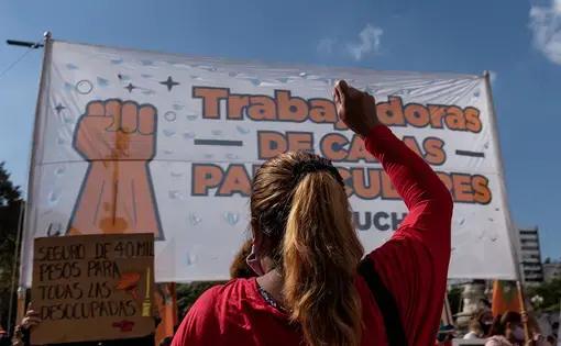 Someone, with their back to the camera, raises their fist during a protest.