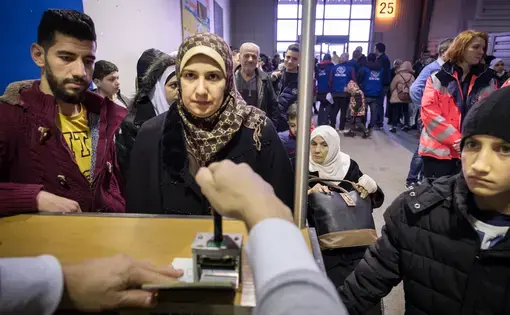 An immigration officer stamps the passports of a Syrian family who have just landed at Hanover airport