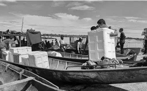 A man carries a box as he walks to the boat.