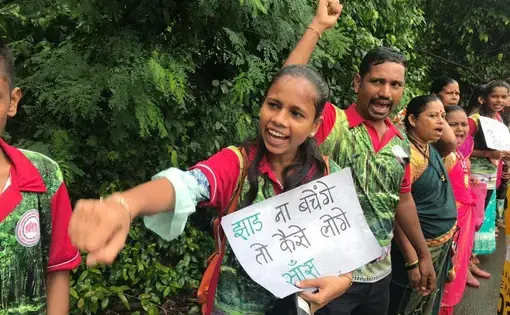 A young girl holds a handwritten sign in protest with other people