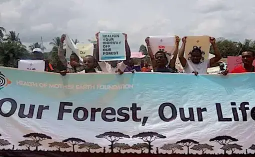 Ten people are walking and holding a poster called "Our Forest, Our Life" in black letters.