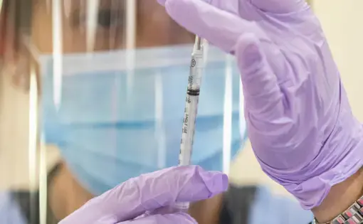 a nurse loads a syringe with a vaccine