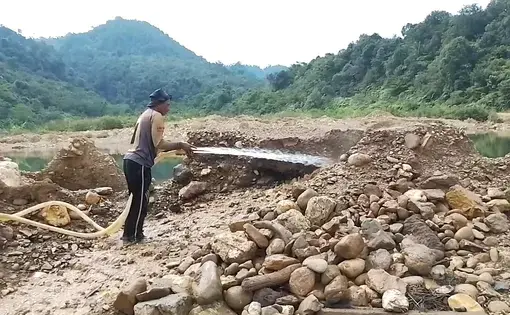 A man sprays water at a gold mine.