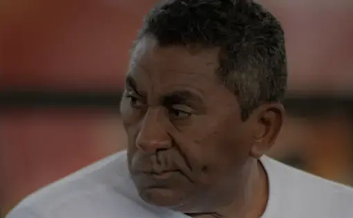 A fisherman wears a white shirt and talks.