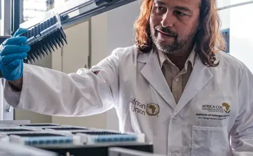 A man examining pipette heads under a fume hood
