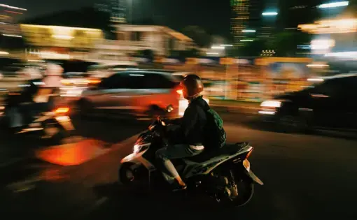 A person on a motorbike in traffic at night
