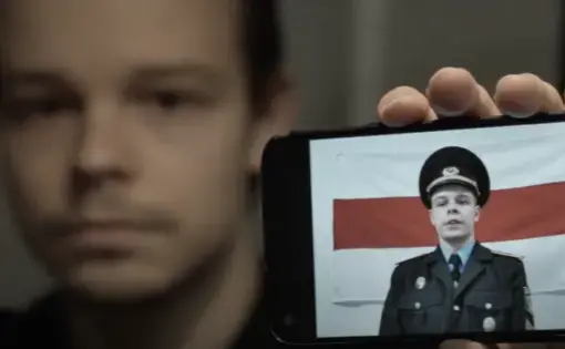 man holding phone with image of soldier in front of a flag for the Belarusian Democratic Republic