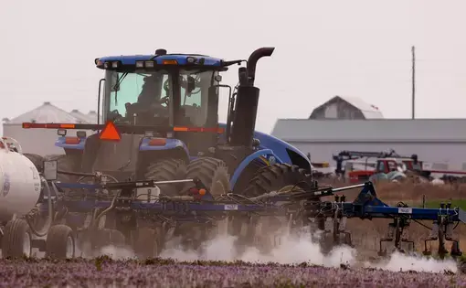 Tractor with fertilizer spreader on farm
