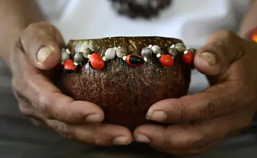 A closeup of hands holding an embellished bowl.