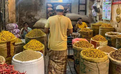 A man stands among bags of yellow spices