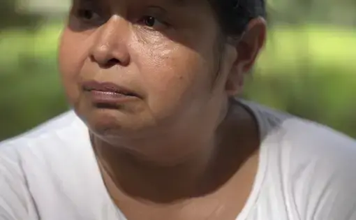 A mid-shot of a woman in white shirt donning a cap.