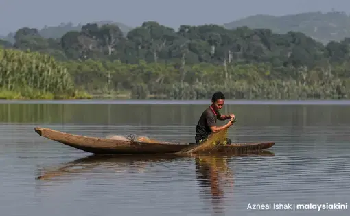 A man fishes in the middle of a lake on a boat.