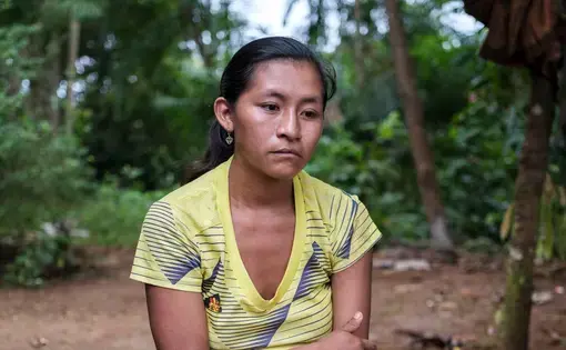 A woman in yellow t-shirt sits in despair.