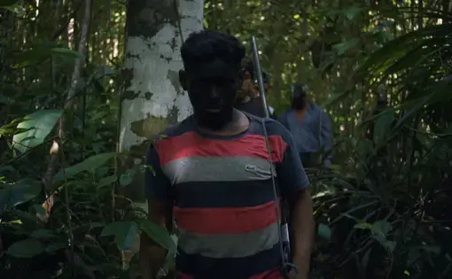An indigenous man walks through the Amazon rainforest.