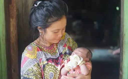 A woman cradles a baby in her arms.