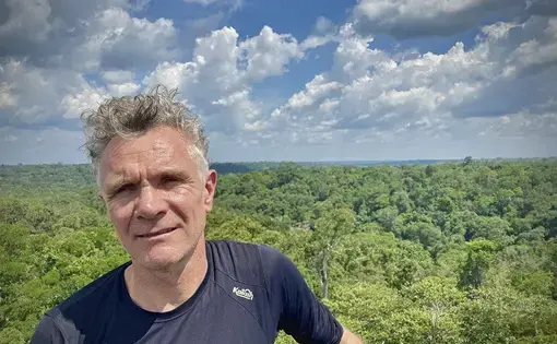A picture of Dom Philips in a blue t shirt against the lush green forest.