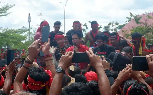 A crowd of people wearing red t-shirts, cheering on.