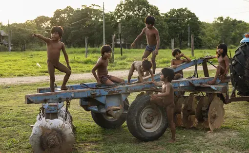 Native children stand hither thither atop a cart.