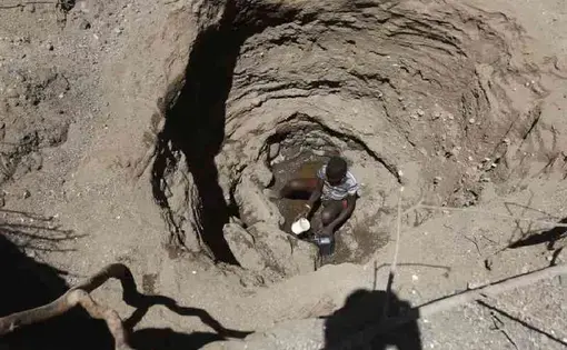 A person sits at the bottom of a pit.