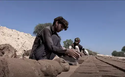 Young men lay bricks to dry