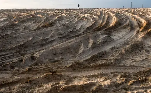 A boy walks atop massive sand dunes.