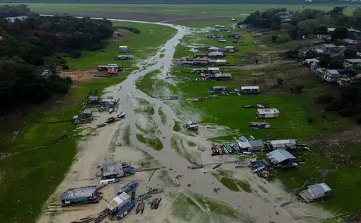 Floating houses and boats lie stranded on a soaked up river during an abnormal dry season.