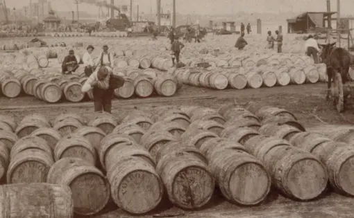 black and white photo of men standing with many barrels