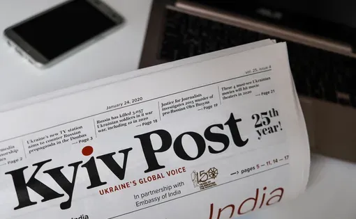 Reading the front page of Ukrainian newspaper Kyiv Post at home.