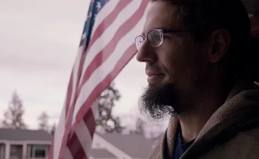 Man standing in front of flag