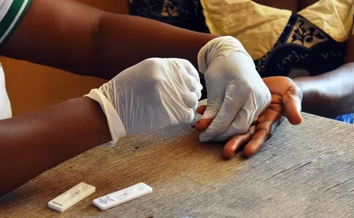 Medical Outreach Nonprofit Charity Organization Health Worker with Patient in Ghana, East Africa doing a Finger Prick for HIV and Malaria Blood Testing Kits
