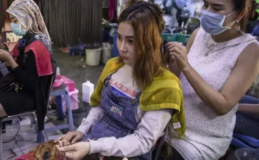 Hair salon owner Meyly Heng places a hair extension on a customer in Phnom Penh. Image by Paula Bronstein. Cambodia, 2019.