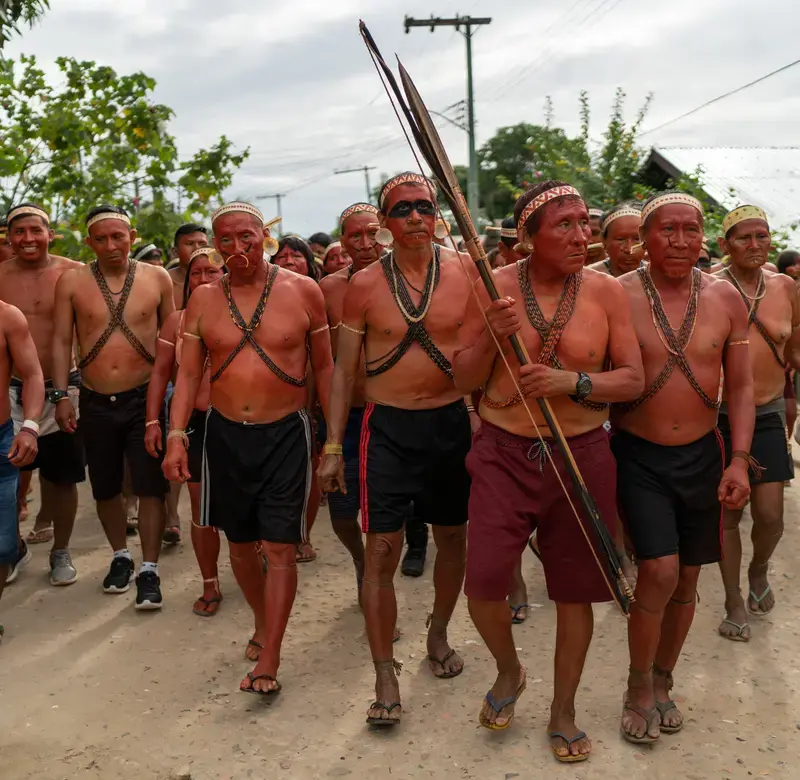 a group of Indigenous people wearing body paint walk in a row in a demonstration