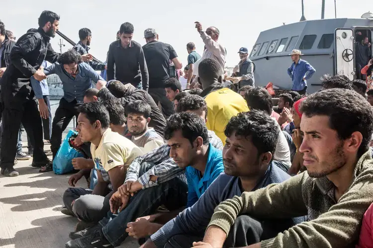 Migrants from Bangladesh and Morocco disembark a warship operated by the Libyan navy after their boat was intercepted at sea.&nbsp;Image by Peter Tinti. Libya, 2017.