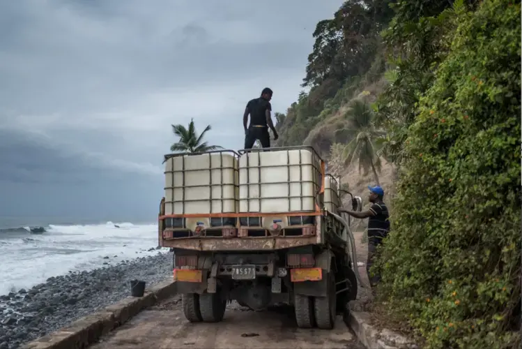 At a natural spring on Anjouan, men filled tanks with water to be transported to villages in the interior where it is in short supply. Image by Tommy Trenchard for The New York Times. Comoros, 2019.