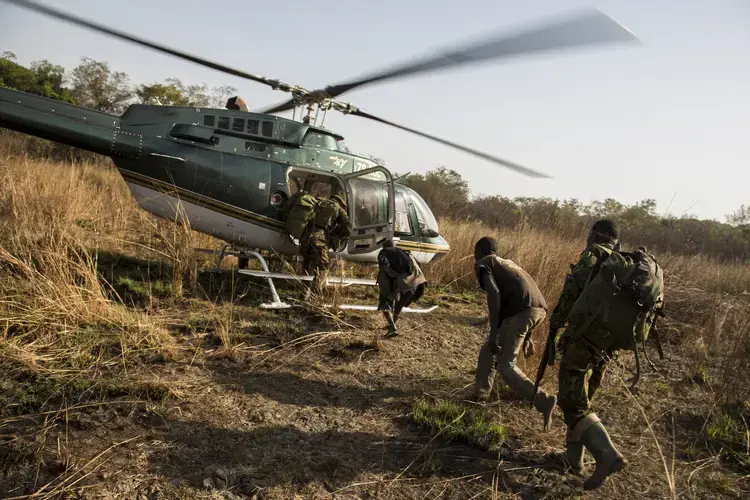 Rangers escort two poachers onto a helicopter after&nbsp;catching them hunting game in the Chinko wildlife reserve. Image by Jack Losh. Central African Republic, 2018.