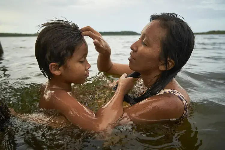Tupí takes a bath with her 10-year-old son. Image by Pablo Albarenga. Brazil, 2019.