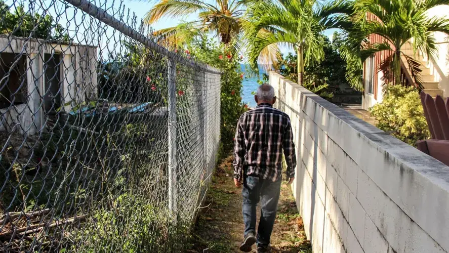Ismael Guadalupe Ortiz walks between buildings to the beach around the Bravos de Boston neighborhood, where vacation homes, small hotels and Airbnbs proliferate. Image by Kari Lydersen. Puerto Rico, 2019.