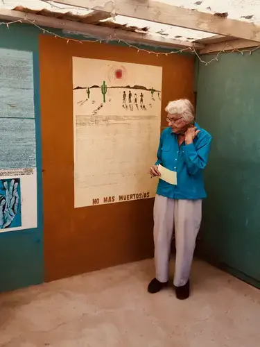 Campbell&nbsp;speaks to a “border immersion” group in her backyard shrine. When Americans come to Juárez on educational trips, they often stop at Campbell’s house, Casa Tabor. She leads a discussion about foreign policy inside and then takes her visitors out to the shrine, where she hands each person a Sharpie and a paper slip with a new name to write on the wall.&nbsp;Image by Lily Moore-Eissenberg. Mexico, 2019.