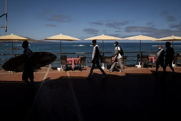 Asylum-seekers Kassim Diallo and Yamadou Konaré of Mali walk next to the beach in Las Palmas de Gran Canaria, Spain, on Thursday, Aug. 20, 2020. Image by Emilio Morenatti/AP Photo. Spain, 2020.