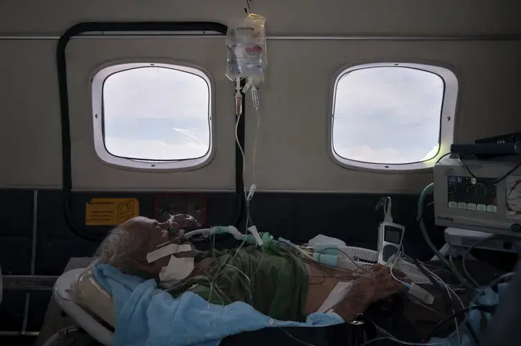 COVID-19 patient Sildomar Castelo Branco, 89, is treated onboard an aircraft as he is transferred from Santo Antônio do Iça to a hospital in Manaus in Brazil's Amazon state, Tuesday, May 19, 2020. Image by AP Photo/Felipe Dana. Brazil, 2020.