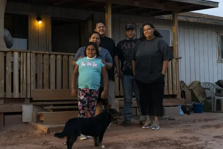 From left, Annabelle Dinehdeal, 8; Maria Cruz, Christina Dinehdeal, Eugene Dinehdeal, Angelina Dinehdeal, and their dog, Wally, pose for a photo on the Dinehdeal family compound in Tuba City, Ariz., on the Navajo reservation on April 20, 2020. The family has been devastated by COVID-19. Image by AP Photo/Carolyn Kaster. United States, 2020.