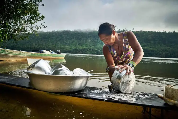 Indigenous woman wash dishes on the river Arinos. Brazil, 2019. Image by Pablo Albarenga.