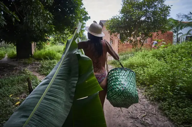 Tupi collects leaves for her community work to decorate a table. Image by Pablo Albarenga. Brazil, 2019.