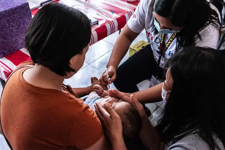 Rosalie Natividad administers a vaccine to a baby in a clinic.&nbsp;Image by Xyza Cruz Bacani. Philippines, 2020.