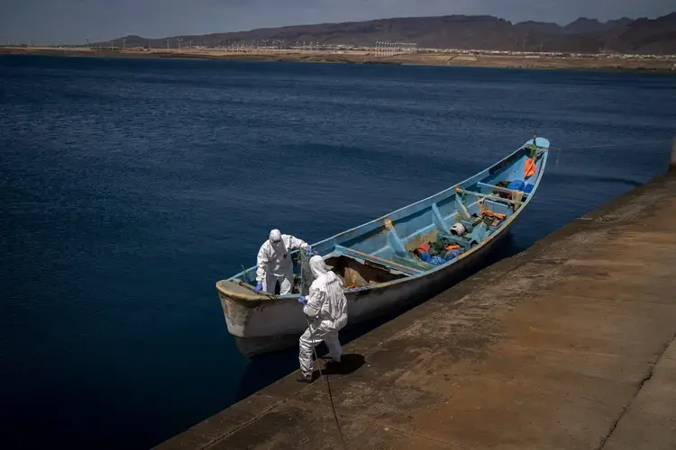 Police officers inspect a boat where 15 Malians were found dead adrift in the Atlantic on Thursday, Aug. 20, 2020, in Gran Canaria island, Spain.&nbsp;Image by Emilio Morenatti/AP Photo. Spain, 2020.