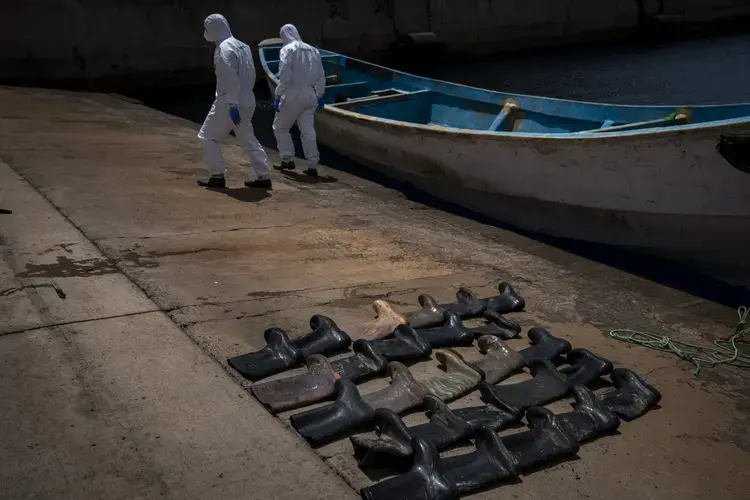 Waterproof boots are placed on the ground by police officers as they inspect a boat where 15 Malians were found dead adrift in the Atlantic on Thursday, Aug. 20, 2020, in Gran Canaria island, Spain. Image by&nbsp;Emilio Morenatti/AP Photo. Spain, 2020.jpeg
