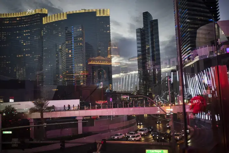 Casinos and other businesses are seen reflected in the glass walls of an overpass along the Las Vegas Strip. The coronavirus hit the Las Vegas economy particularly hard. Visitors to the area plummeted by more than 90 percent in a little over a month. The state's unemployment rocketed to 28 percent, the worst in the nation and a level not seen even during the Great Depression. Image by Wong Maye-E /&nbsp;AP Photo. United States, 2020.