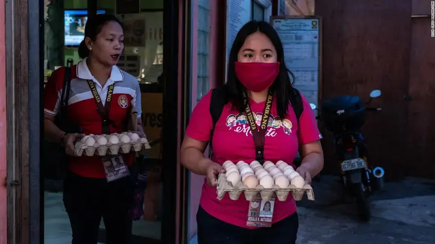 Rosalie Natividad wears a makeshift mask as she carries eggs to local families.&nbsp;Image by Xyza Cruz Bacani. Philippines, 2020.