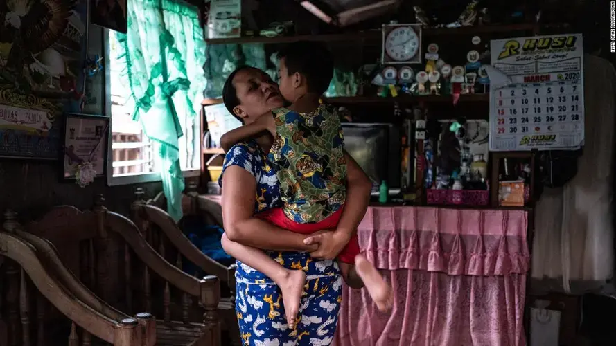 April Abrias hugs her son, Yohan, inside their home after she has disinfected and changed her clothes.&nbsp;Image by Xyza Cruz Bacani. Philippines, 2020.
